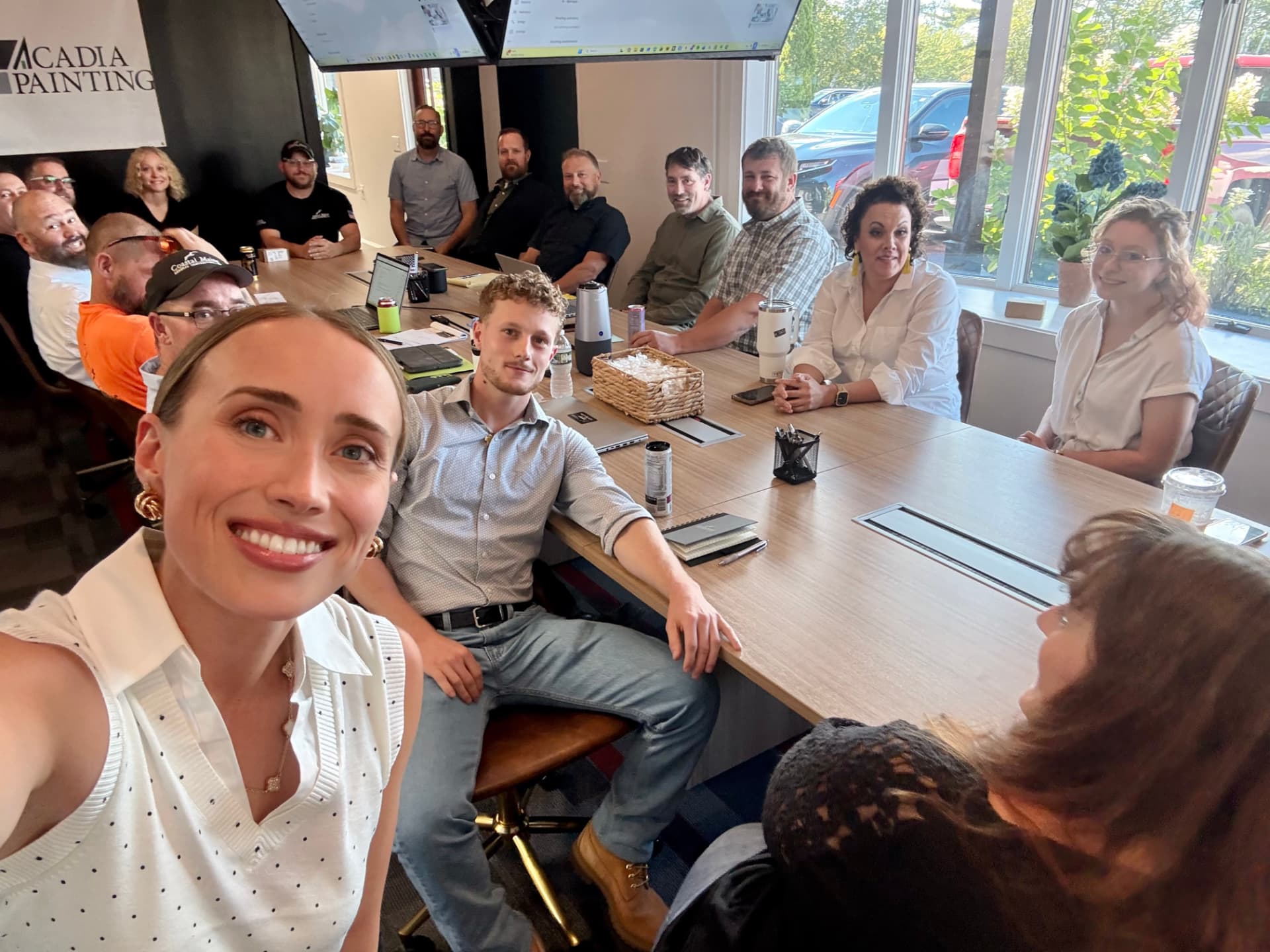 Sarah Sullivan taking a selfie with a team in a meeting room